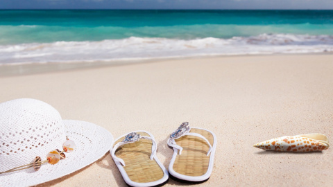  Un sombrero y unas sandalias en una playa. PIXABAY