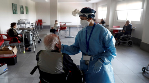 Una sanitaria atiende a un anciano alojado en una residencia en el barrio madrileño de Villaverde, mientras se procede a la desinfección de las instalaciones para evitar la propagación del coronavirus. EFE/Mariscal