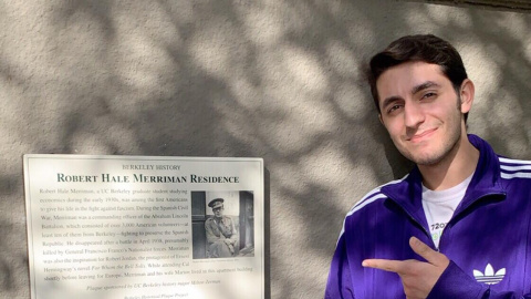 Milton Zerman posa junto a la placa conmemorativa de Robert Merriman colocada en la fachada del antiguo hogar de los Merriman en Berkeley.