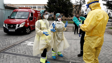 Dos enfermeras que acaban de trasladar en ambulancia a un enfermo que ha dado positivo en el test del COVID-19 solicitan ayuda de un efectivo de la DYA Navarra que en coordinación con el departamento de Salud ha implantado un túnel de desinfección en e