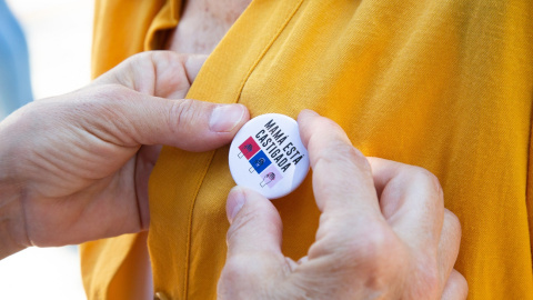  Una mujer coloca una chapa a otra, en una concentración enmarcada en la campaña #MamáEstáCastigada, frente a la Delegación del Gobierno, a 29 de mayo de 2021, en Badajoz, Extremadura (España). / JAVIER PULPO / Europa Press