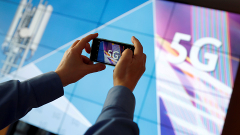 Un periodista toma una foto con teléfono móvil del logotipo 5G antes de la subasta de espectro para servicios 5G en la sede de Bundesnetzagentur, en Mainz (Alemania). REUTERS / Kai Pfaffenbach