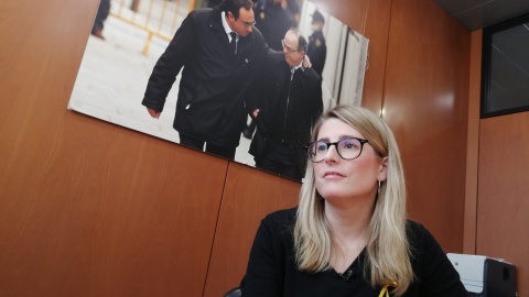 Elsa Artadi durant l'entrevista realitzada al Parlament amb una foto de Josep Rull i Jordi Turull al fons.