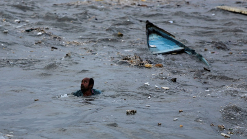 Un pescador nada a la orilla después de que su bote se volcó debido a las fuertes olas que se avecinaban antes de la llegada del ciclón Vayu en Veraval, India | Reuters