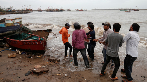 Los pescadores mueven un barco de pesca a un lugar más seguro a lo largo de la costa antes de la llegada a tierra del Ciclón Vayu en Veraval.