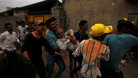 Un grupo de pescadores auxilian a un compañero que resultó herido después de que su bote volcara debido a las fuertes olas a consecuencia del 'ciclón Vayu' | Reuters