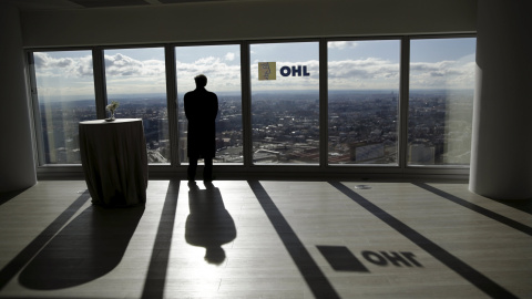 Un hombre mira a través de un ventanal de la sede en Madrid de la constructora OHL. REUTERS/Andrea Comas