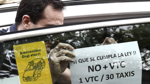 Un taxista pega en su taxi un cartel de protesta contra el incumplimiento de la proporción 1/30 entre licencias VTC y taxi. EFE