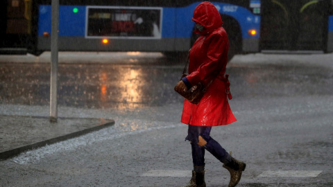 Una mujer camina por la calle durante la tormenta registrada esta mañana en Madrid. EFE/ Fernando Alvarado