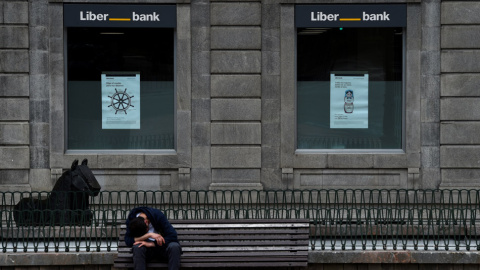 Un hombre sentado frente a la sede de Liberbank en Oviedo. REUTERS/Eloy Alonso