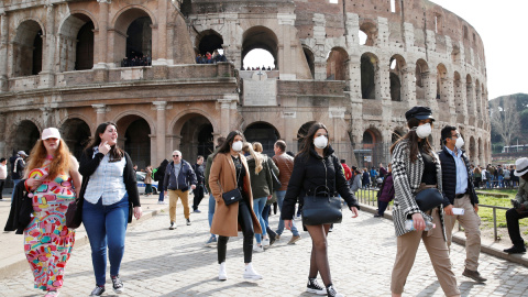 Turistas pasean junto al coliseo en Roma portando mascarillas. / Reuters