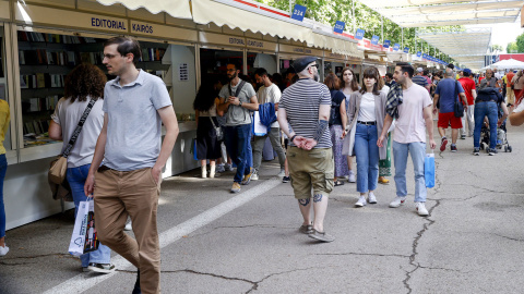 Varias personas caminan entre las casetas de la Feria del Libro de Madrid, este miércoles en el Parque del Retiro. EFE/ J P Gandul