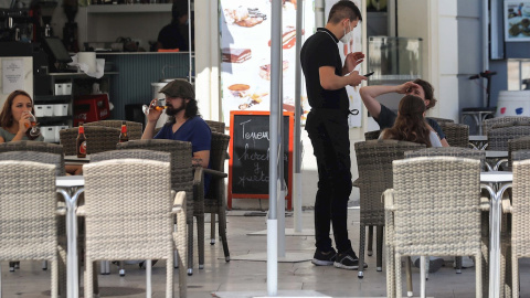 un camarero atiende a unos clientes en la terraza de un bar. EFE/Ana Escobar