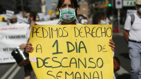 Una mujer sujeta una pancarta en la que se lee 'Pedimos derecho a 1 día de descanso semanal' durante una manifestación de los médicos internos residentes (MIR) en Madrid. /Europa Press