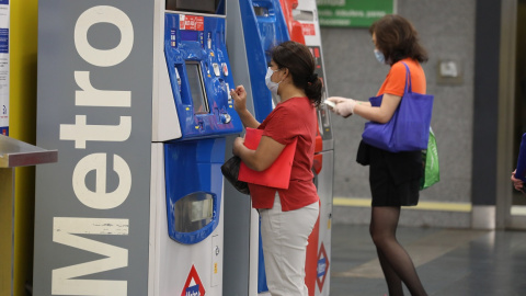 Dos personas hacen uso de las máquinas expendedoras de viajes del Metro de Madrid. E.P./Marta Fernández