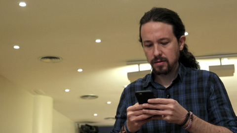 El secretario general de Podemos, Pablo Iglesias, mira su móvil poco antes de comparecer ante los medios de comunicación en el Congreso. EFE/Chema Moya