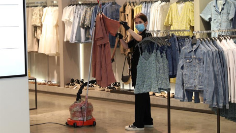 Una dependienta desinfecta la ropa con una plancha de vapor en el interior de una tienda. EFE/Rodrigo Jiménez