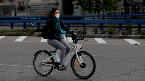 Una mujer con mascarilla y guantes usa una bicicleta del servicio BiciMAD, en Madrid. EFE/Chema Moya