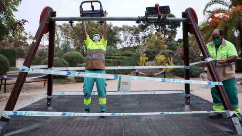 Varios operarios precintan unos columpios en un parque de Valencia este viernes | EFE