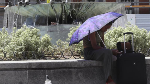 Una mujer se protege del sol con un paraguas en la madrileña Puerta del Sol coincidiendo con el inicio de la primera "ola de calor" del año. EFE/Ballesteros