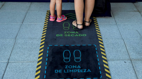 Una madre y su hija se limpian los zapatos durante la reapertura de una escuela infantil en Madrid. EFE/ Rodrigo Jiménez/Archivo