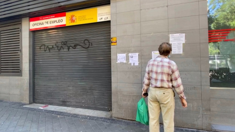 Una persona observa uno de los carteles con instrucciones para hacer trámites por internet colocados en la fachada de una oficina de empleo en Madrid. E.P./Eduardo Parra