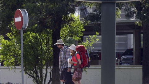 Unos turistas pasan junto a un termómetro por el centro de Córdoba que se encuentra en alerta amarilla por altas temperaturas. EFE/Salas