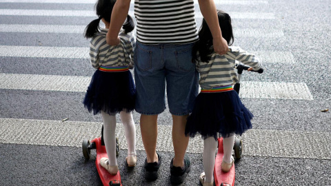 Dos niñas esperan para cruzar en un paso de cebra. / REUTERS