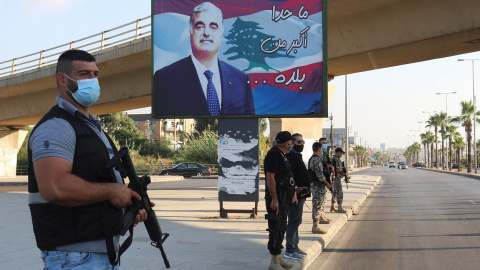 Miembros de las fuerzas de seguridad montan guardia en Sidón, al sur del Líbano, cerca de un cartel con la imagen del exprimer ministro libanés, Rafik al-Hariri, quien murió en un atentado suicida en 2005. REUTERS / Aziz Taher