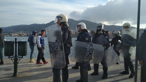 Policías griegos cargan contra los refugiados en el puerto de Mitilini.