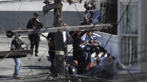 Las transeúntes  están siendo evacuados con las manos por encima de sus cabezas por orden de la policía en el área de un incidente de tiroteo en una instalación de United Parcel Service (UPS) en San Francisco, California, EE.UU. 14 de junio de 2017. 