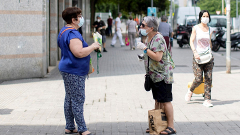 Dos mujeres mantienen la distancia social mientras hablan en una calle de Barcelona. - EFE