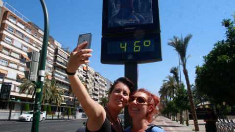 Dos mujeres se fotografían en Córdoba con un termómetro que marca 45 grados en la ciudad. EFE