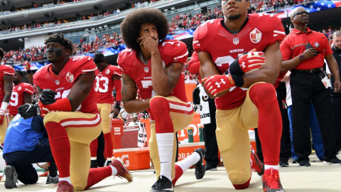 02/10/2016- Los jugadores Eli Harold, Colin Kaepernick y Eric Reid se arrodillan mientras suena el himno de EEUU durante un partido en señal de protesta en 2016. / GETTY IMAGES A TRAVÉS DE AFP