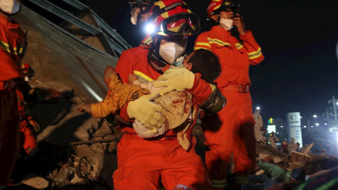 El servicio de rescate saca en brazos a un niño que había quedado sepultado por el derrumbe del centro de cuarentena en Quanzhou./ Xiao Fan (EFE/EPA/FEATURECHINA)