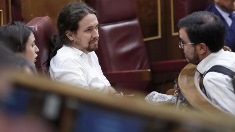 El secretario general de Podemos, Pablo Iglesias conversa con el coordinador general de IU, Alberto Garzón, durante el pleno del Congreso que se celebró el 20 de junio. | CHEMA MOYA (EFE)