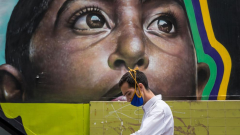 Un hombre con una mascarilla camina frente a un mural este martes en Caracas, Venezuela. /MIGUEL GUTIÉRREZ / EFE