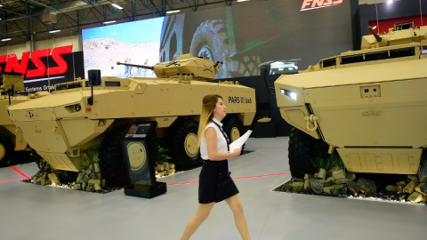 Una mujer pasa junto a un par de vehículos blindados en la Feria Internacioanl de Industria de Defensa, en Estambul. AFP/Yasin Akgul