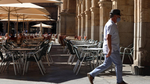 Un hombre con mascarilla pasa frente a una terraza de un restaurante de la plaza mayor de Salamanca, este miércoles. | EFE