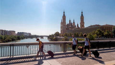 Varias personas con maletas cruzan el Puente de Santiago de Zaragoza. EFE/Javier Belver/Archivo