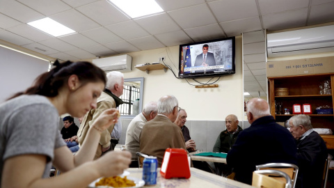 12/03/2020.- Un grupo de ancianos juega a las cartas este jueves en un bar del barrio de Aluche, en Madrid, mientras en la televisión comparece el presidente del Gobierno por el coronavirus. / EFE - MARISCAL