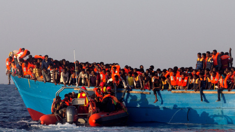 Un barco de rescate de la ONG española Proactiva se acerca a una patera de madera abarrotada de inmigrantes procedentes de Eritrea, frente a la costa de Libia en el Mar Mediterráneo. REUTERS/Giorgos Moutafis