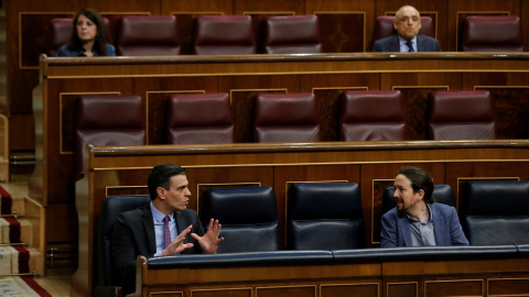 El presidente del Gobierno, Pedro Sánchez, conversa con el vicepresidente segundo, Pablo Iglesias,  durante una sesión de control al Gobierno en el Congreso de los Diputados. E.P./Pool