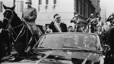 El presidente de Chile, Salvador Allende, saluda a sus seguidores desde su coche descubierto, en Santiago, pocas semanas después de su elección. A su lado, a caballo, es escoltado por el general Augusto Pinochet. AFP