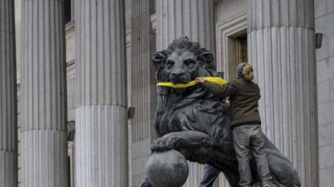 Una activista de Greenpeace amordaza los leones del Congreso de los Diputados. - Foto: EFE