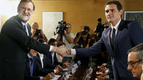 El jefe del Gobierno, Mariano Rajoy,iz., y el líder de Ciudadanos, Albert Rivera, se estrechan la mano durante la reunión de sus respectivas delegaciones en la que van a certificar el acuerdo de investidura-.EFE/Sergio Barrenechea