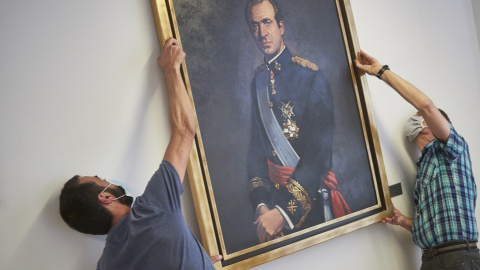 Dos operarios retiran del retrato del rey emérito Juan Carlos I de la Sala de Gobierno del Legislativo foral del Parlamento de Navarra. Eduardo Sanz / Europa Press / Archivo