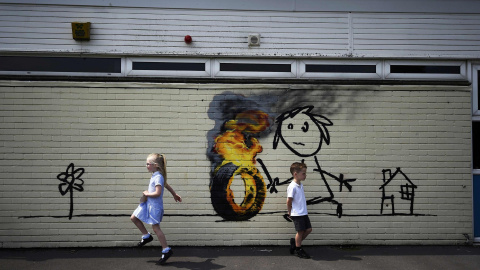 Niños frente a un graffiti del artista Banksy pintado en el exterior de un aula de la Escuela Primaria Bridge Farm en Bristol, Reino Unido.  REUTERS/Dylan Martinez