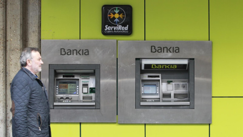 Un hombre pasa frente a los cajeros automáticos de una sucursal de Bankia. E.P.