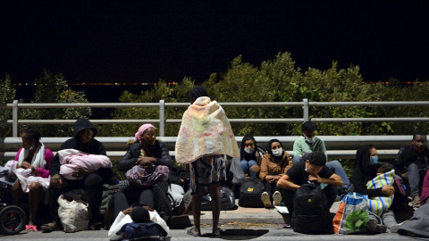 Un grupo de solicitantes de asilo descansa en la carretera, fuera ya del campo de refugiados de Moria, en la isla griega de Lesbos, incendiado esta madrugada.- EFE